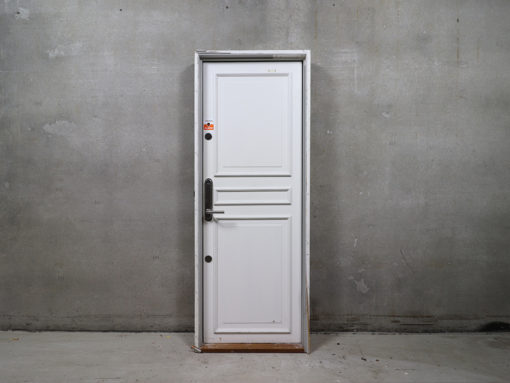 Venstrehængt opgangsdør i karm. Døren er med fyldning på den ene side, glat på den anden og udstyret med rustfri briklås.